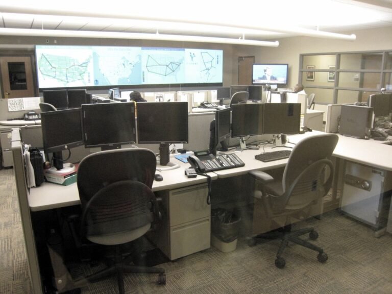 Analysts work at rows of monitors inside a modern cyber security operations centre.
